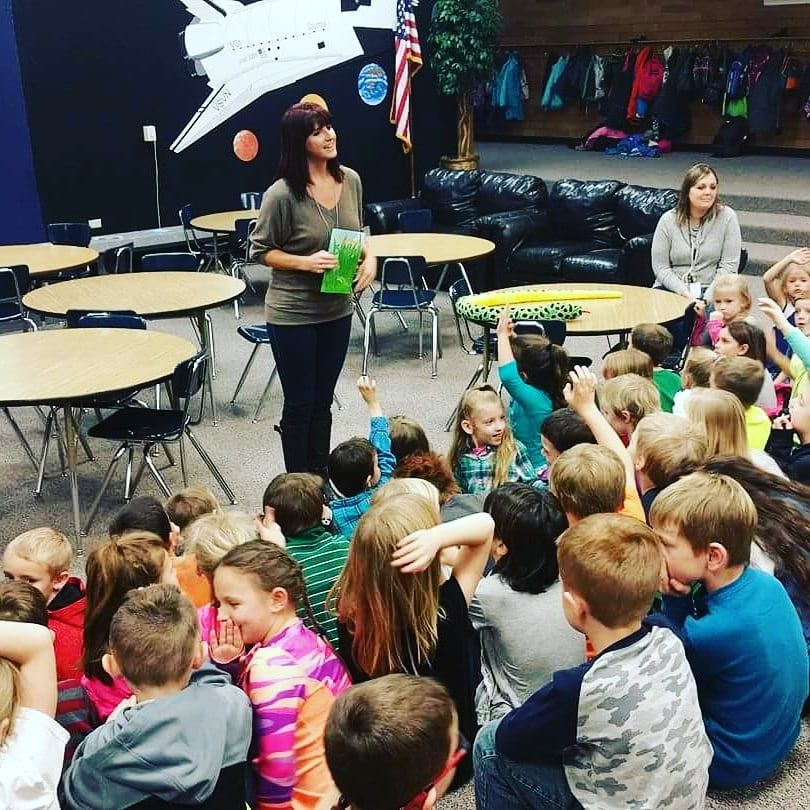 Suzanne Hobbs reading to a room of schoolchildren.